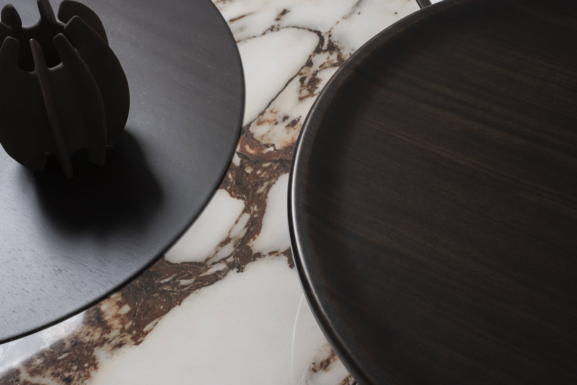 Modern dark wood and black ceramic plates on marble surface, showcasing stylish tableware and home decor from Saloni Furniture.