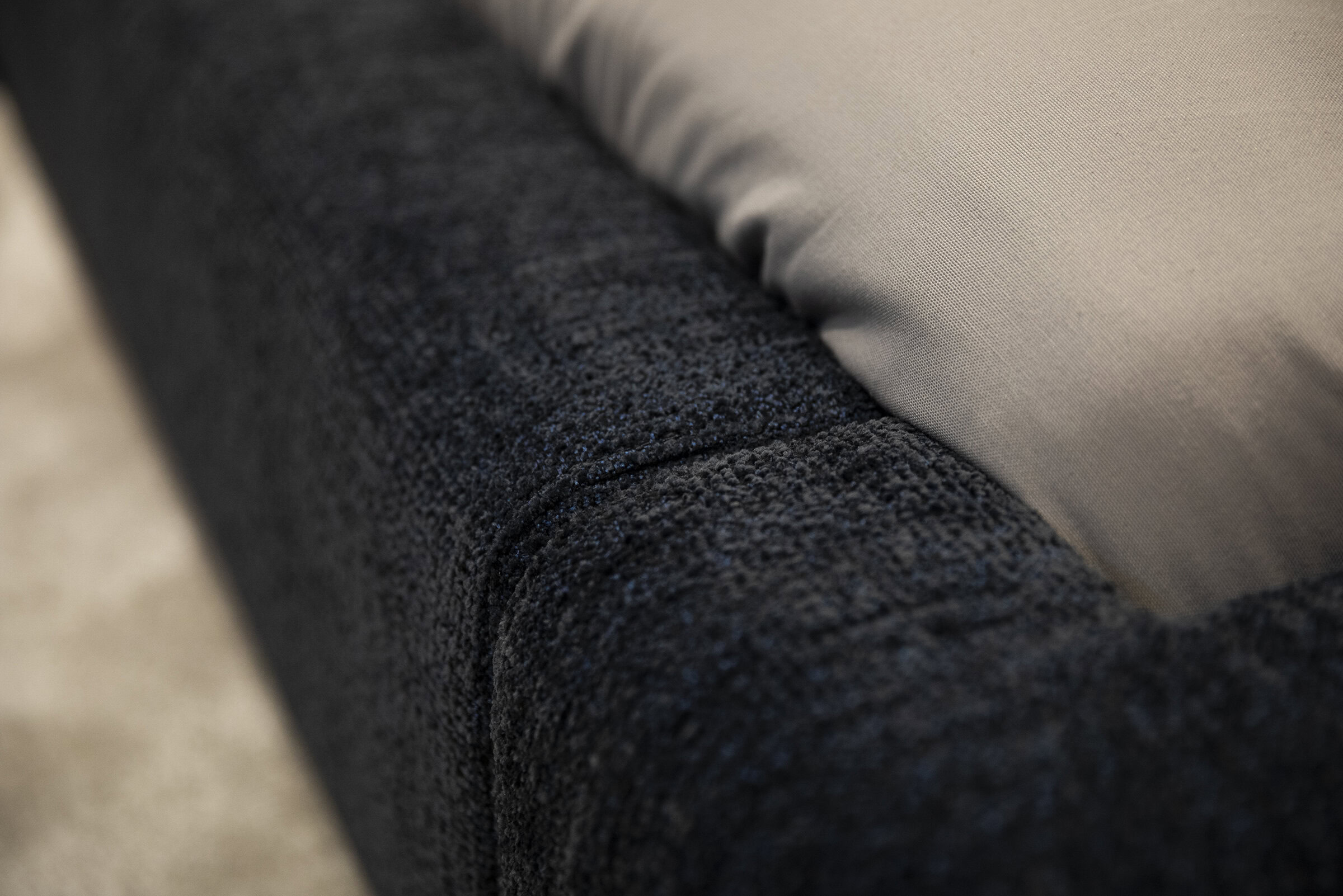 Luxurious dark textured upholstery fabric on a modern sofa, emphasizing quality and comfort in home furniture design.