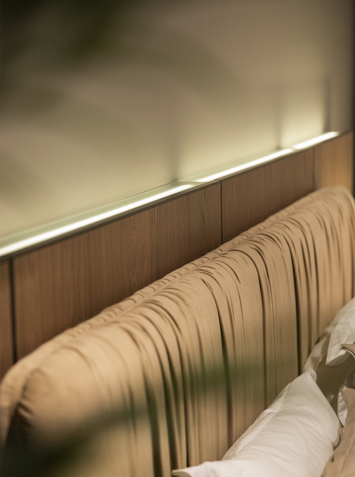 Sleek wooden headboard with vertical panel design, paired with white bedding, showcasing modern bedroom furniture from Saloni Furniture. Perfect for stylish and comfortable bedroom decor.