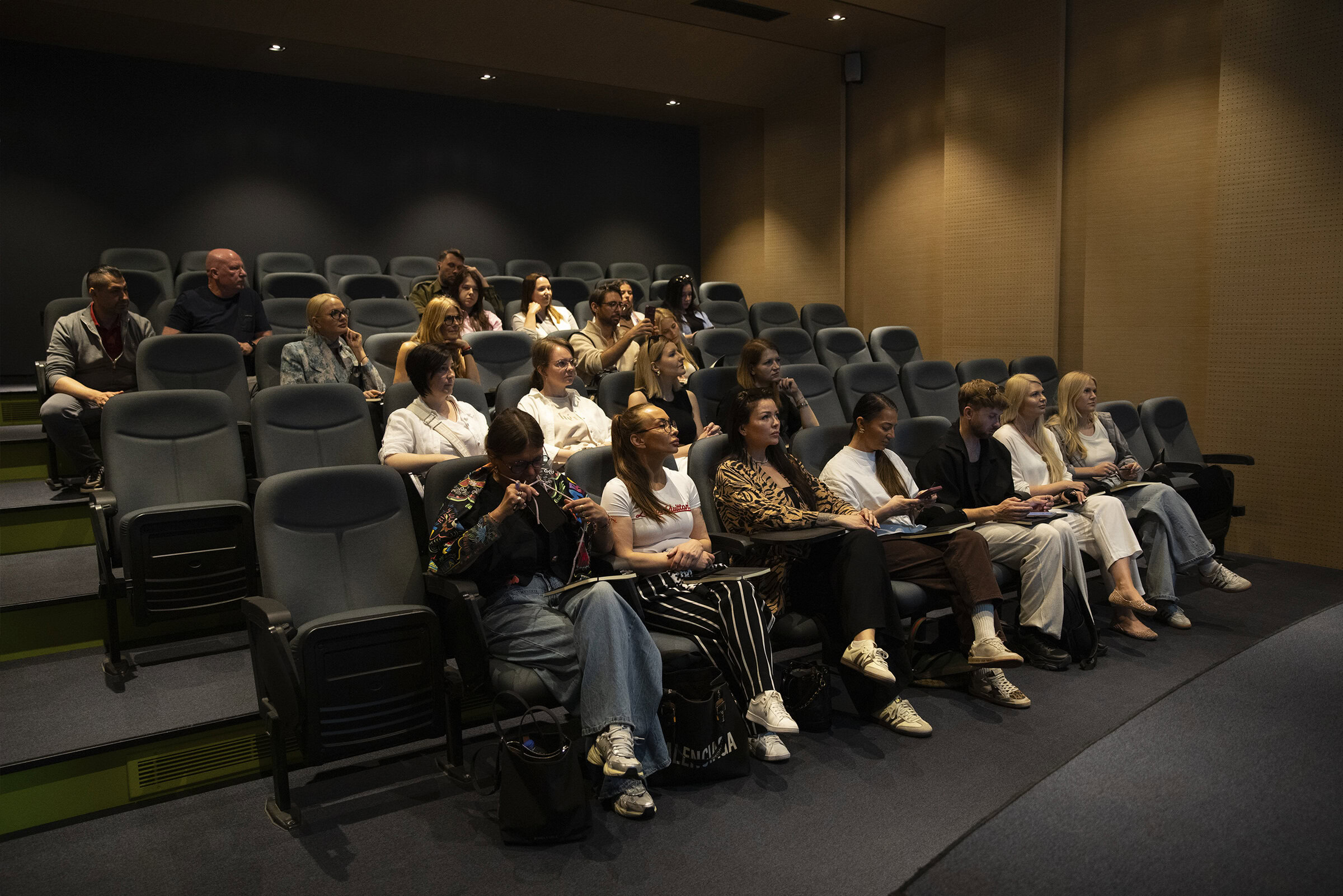Audience seated in a modern conference room, listening attentively to a presentation.