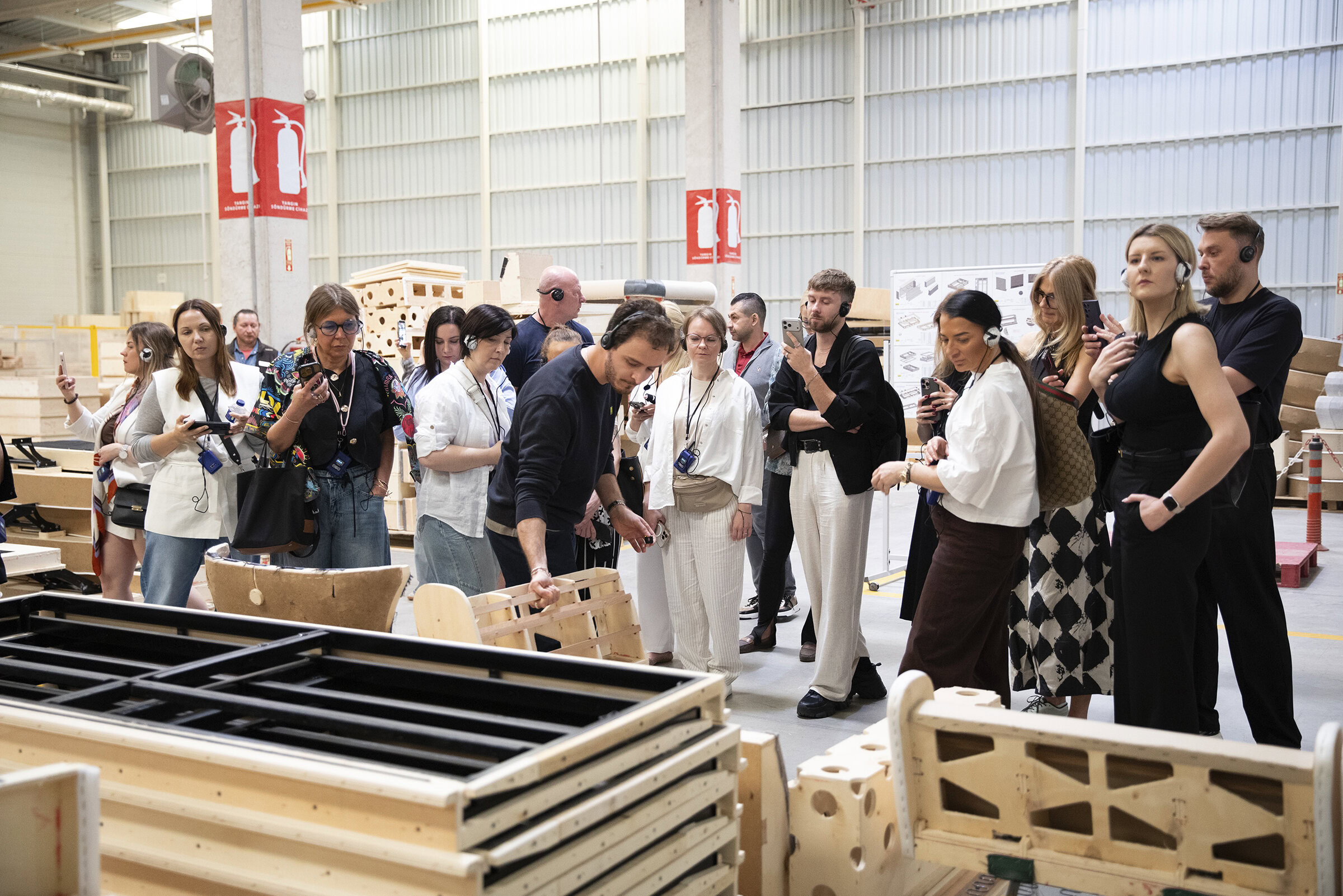 Group of people touring a furniture manufacturing facility, observing wooden furniture pieces and production processes at Saloni Furniture.