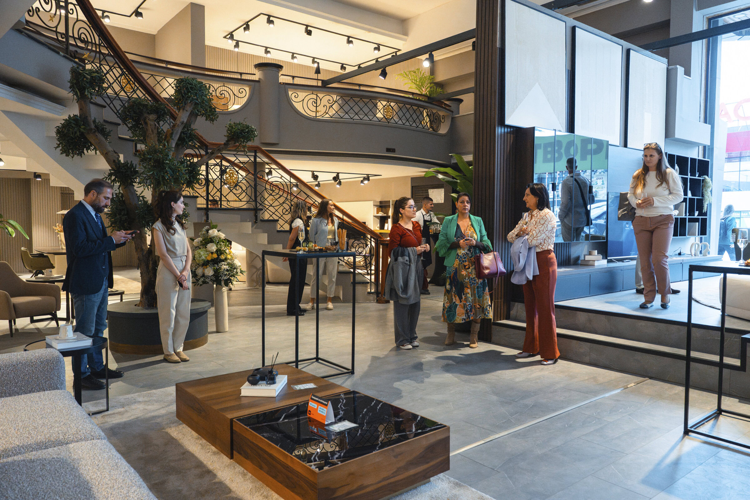 Elegant modern furniture showroom with stylish sofas, tables, and decor, showcasing high-end interior design solutions at Saloni Furniture. Visitors explore contemporary furniture pieces and home decor options.