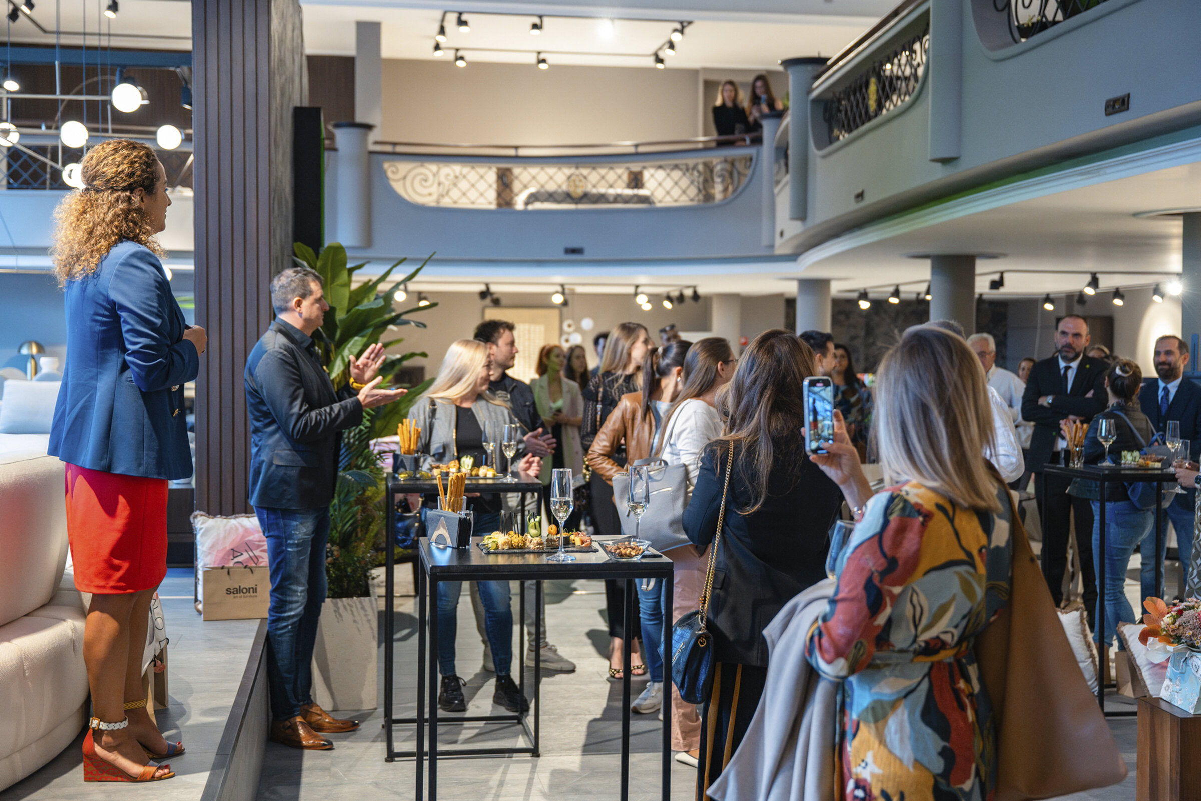 Elegant furniture display with people attending a social event in a modern showroom, showcasing contemporary living room and lounge furniture for stylish home decor.